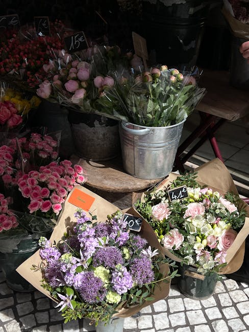 A variety of fresh floral arrangements displayed outdoors, featuring bouquets of pink roses, purple alliums, and mixed pink and white blooms, wrapped in brown paper and arranged in metal buckets and v